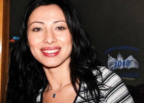 Gül Ateş smiling warmly with blue pendant necklace